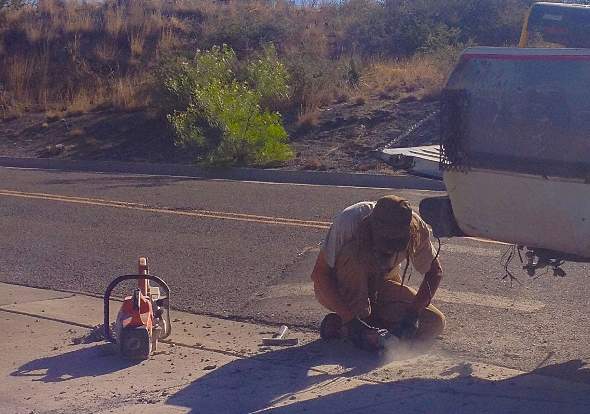 Worker making a water harvesting curb cut